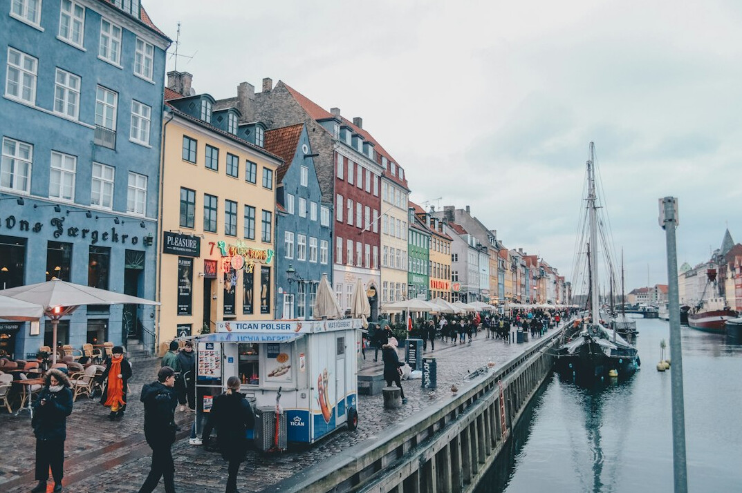 People standing in a long queue on a colorful street in Copenhagen